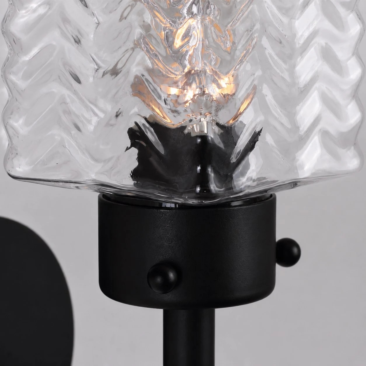Gros plan sur un abat-jour en verre ondulé avec une ampoule à lumière chaude