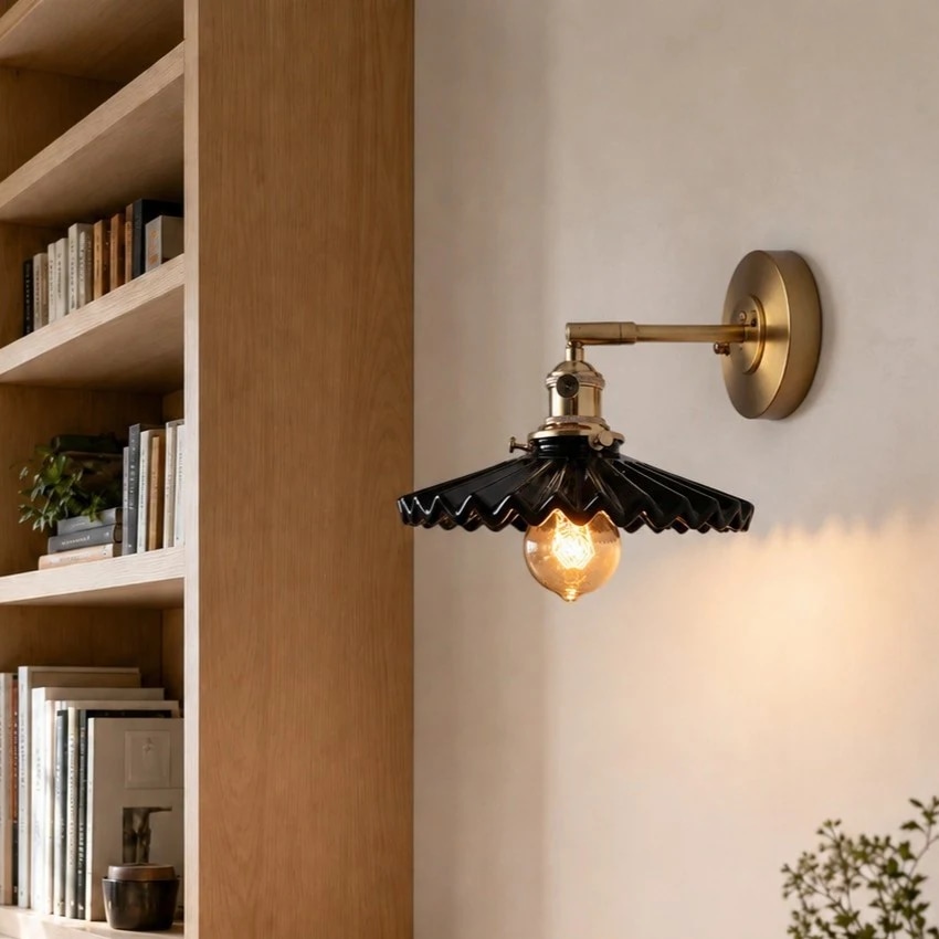Lampada da parete in ceramica nera plissettata installata vicino agli scaffali