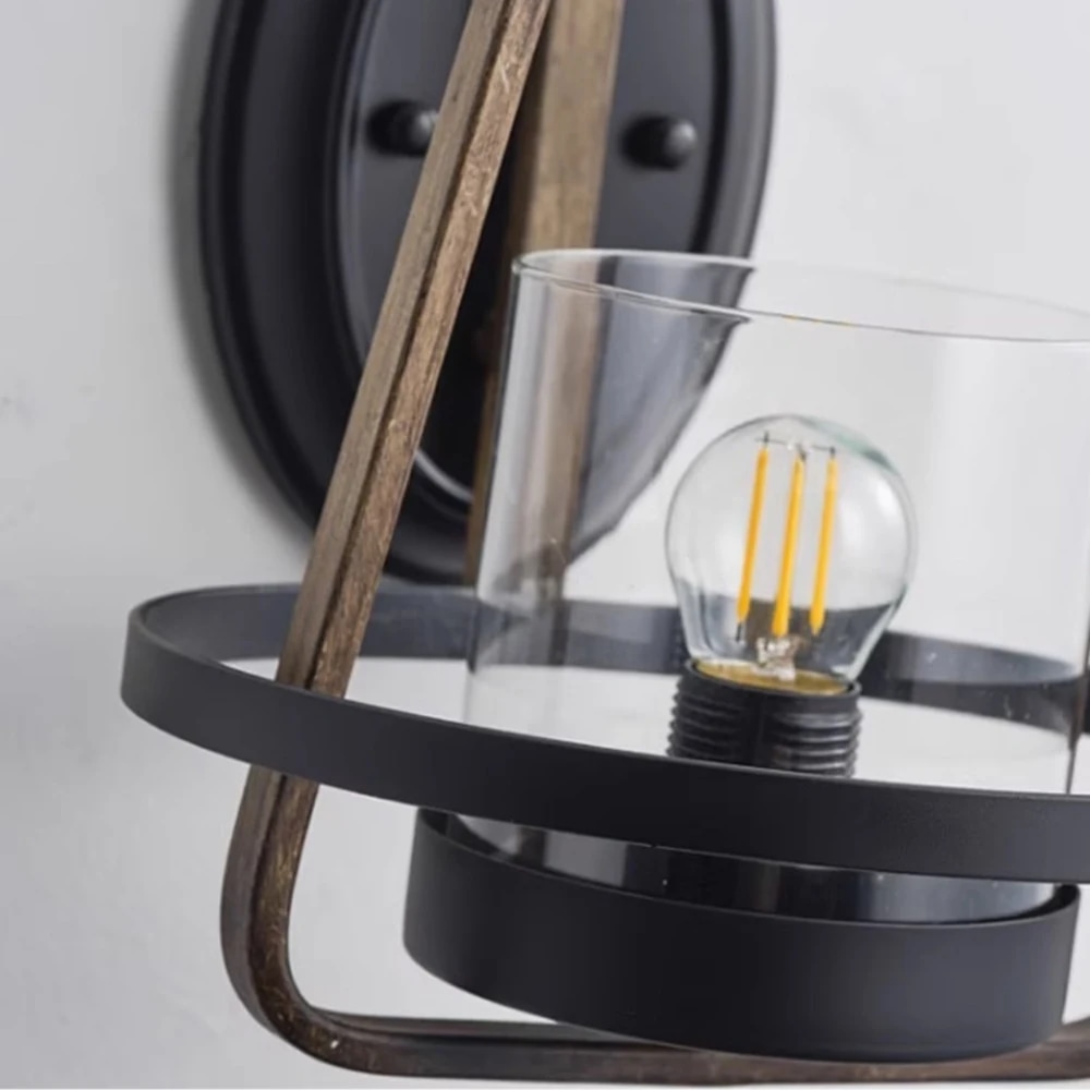 Gros plan sur l'abat-jour en verre transparent et l'anneau inférieur noir d'une applique murale en métal rouillé