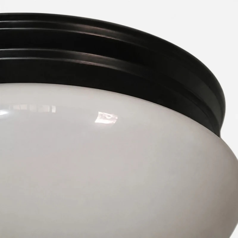 Gros plan sur l'abat-jour en verre opale et le bord noir de la canopée