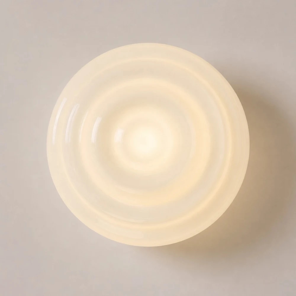 Dettaglio frontale della lampada da parete in vetro scanalato a luce calda.