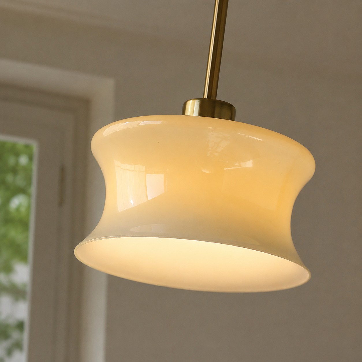 Close view of the curved glass pendant shade glowing warmly