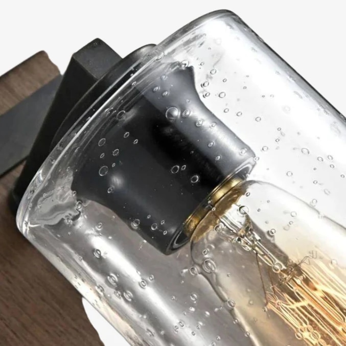 Gros plan sur la douille métallique supérieure et l'abat-jour en verre clair bullé