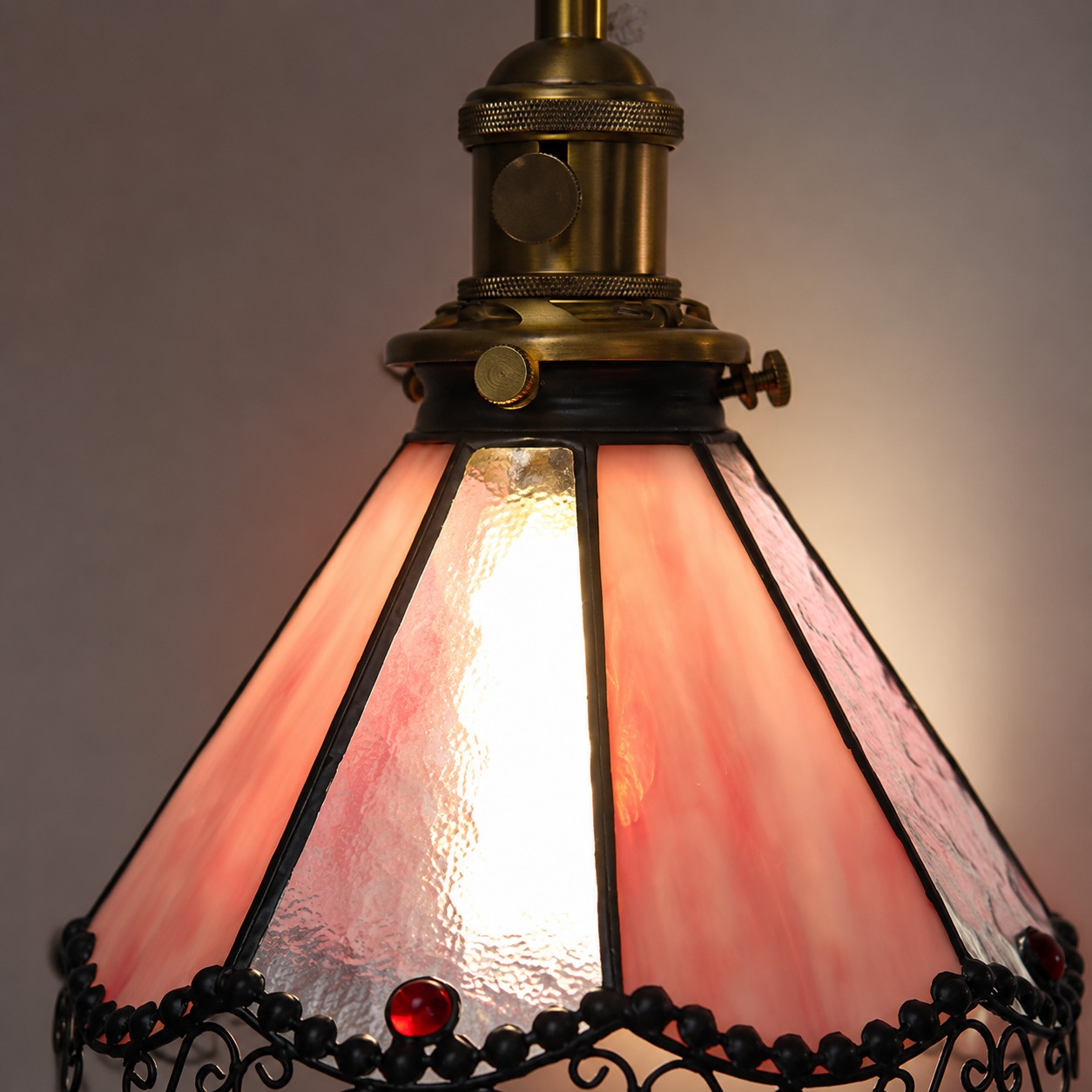 Detalle iluminado de una pantalla de vidrieras rosas