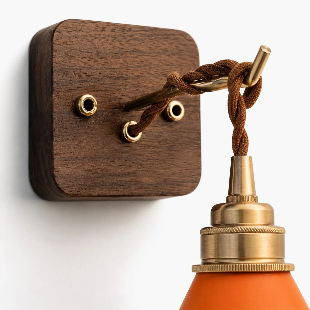 Vista de cerca de la base de madera de la pared, la guía del cable, el collar de latón y la pantalla de cuero.