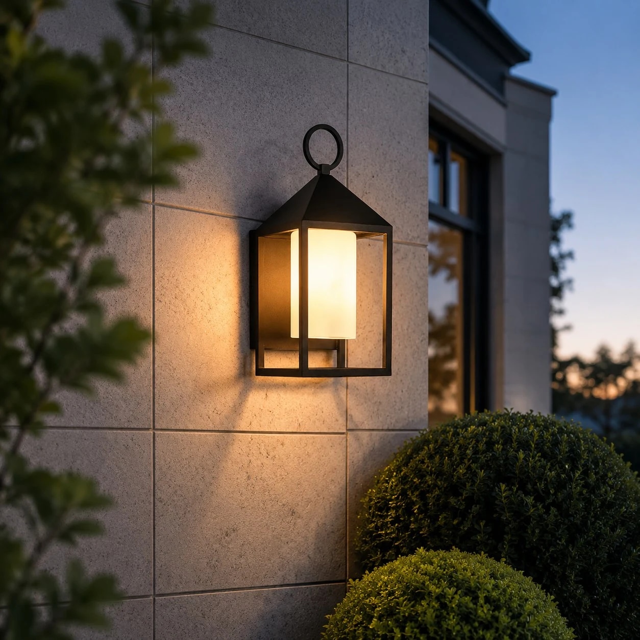 Allora, lampada da parete nera per esterni, montata su una parete esterna con illuminazione calda.