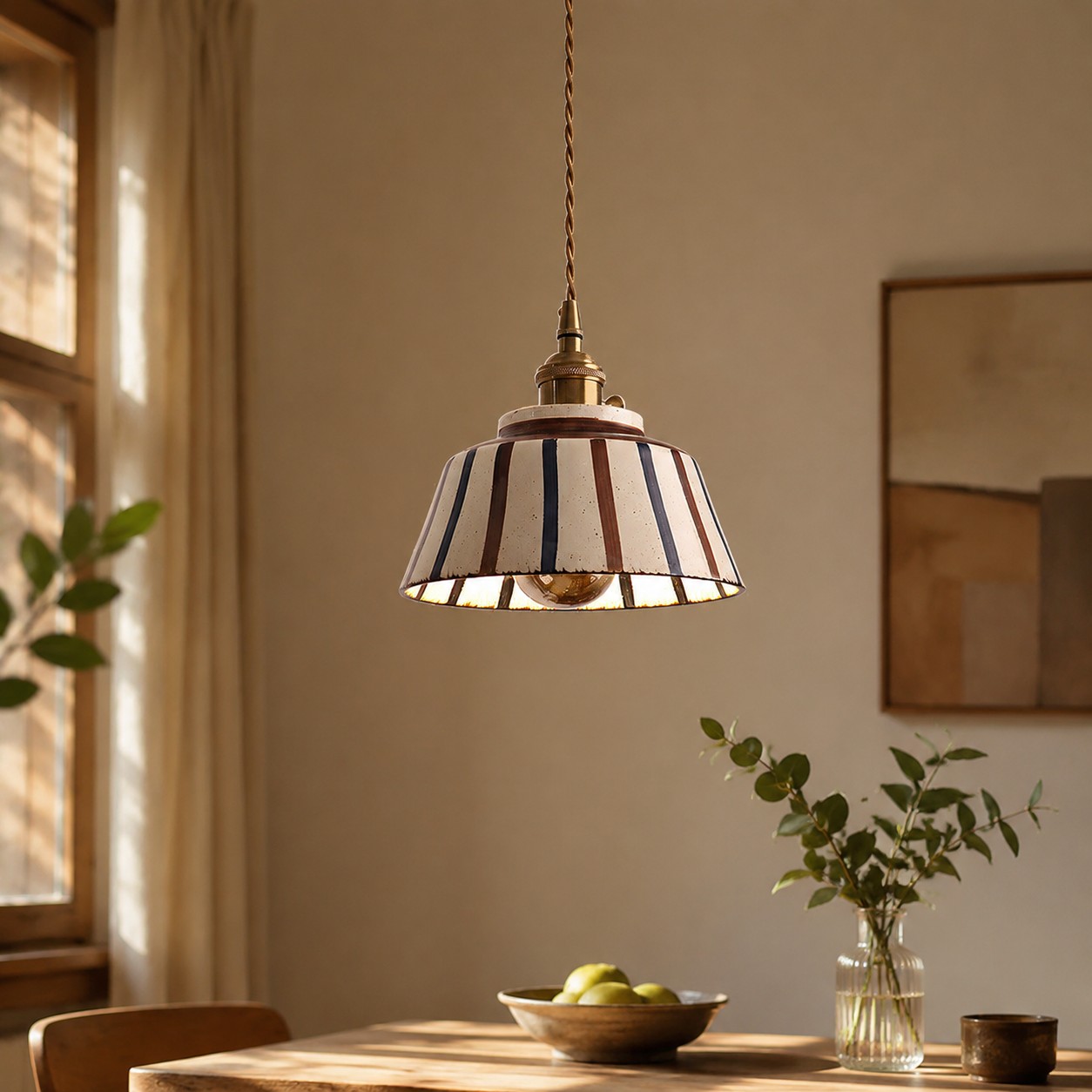 Lampada a sospensione in ceramica a righe sopra un piccolo tavolo da pranzo.