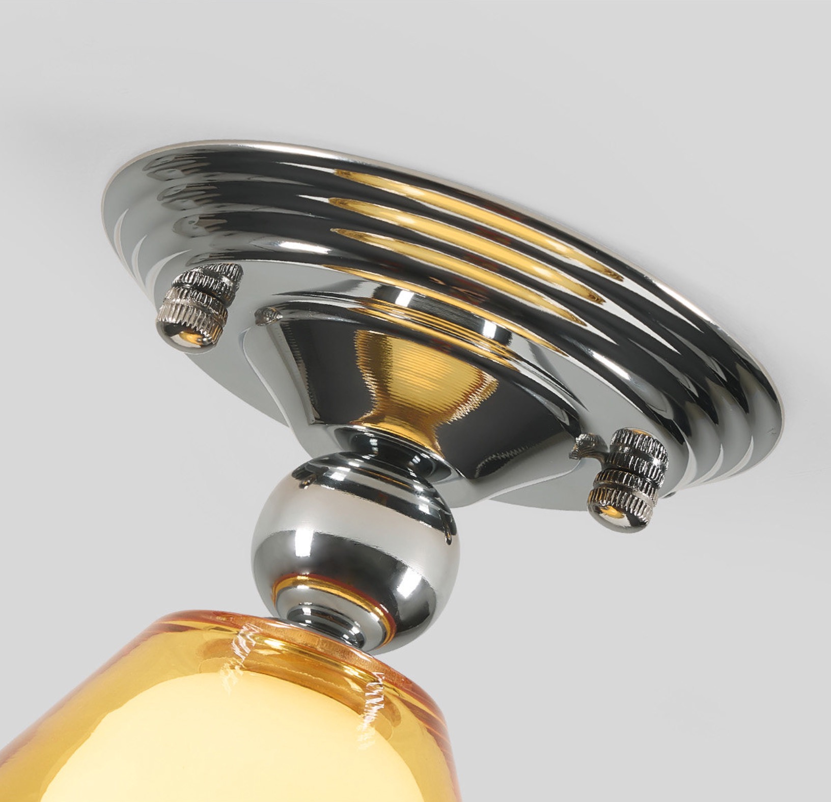 Lámpara de techo de cristal amarillo claro con florón cromado. Detalle del material.