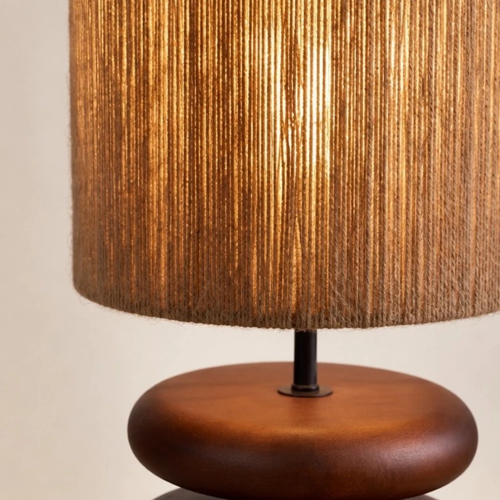 Lampe de table en noyer avec abat-jour en corde de chanvre à la lumière chaude.