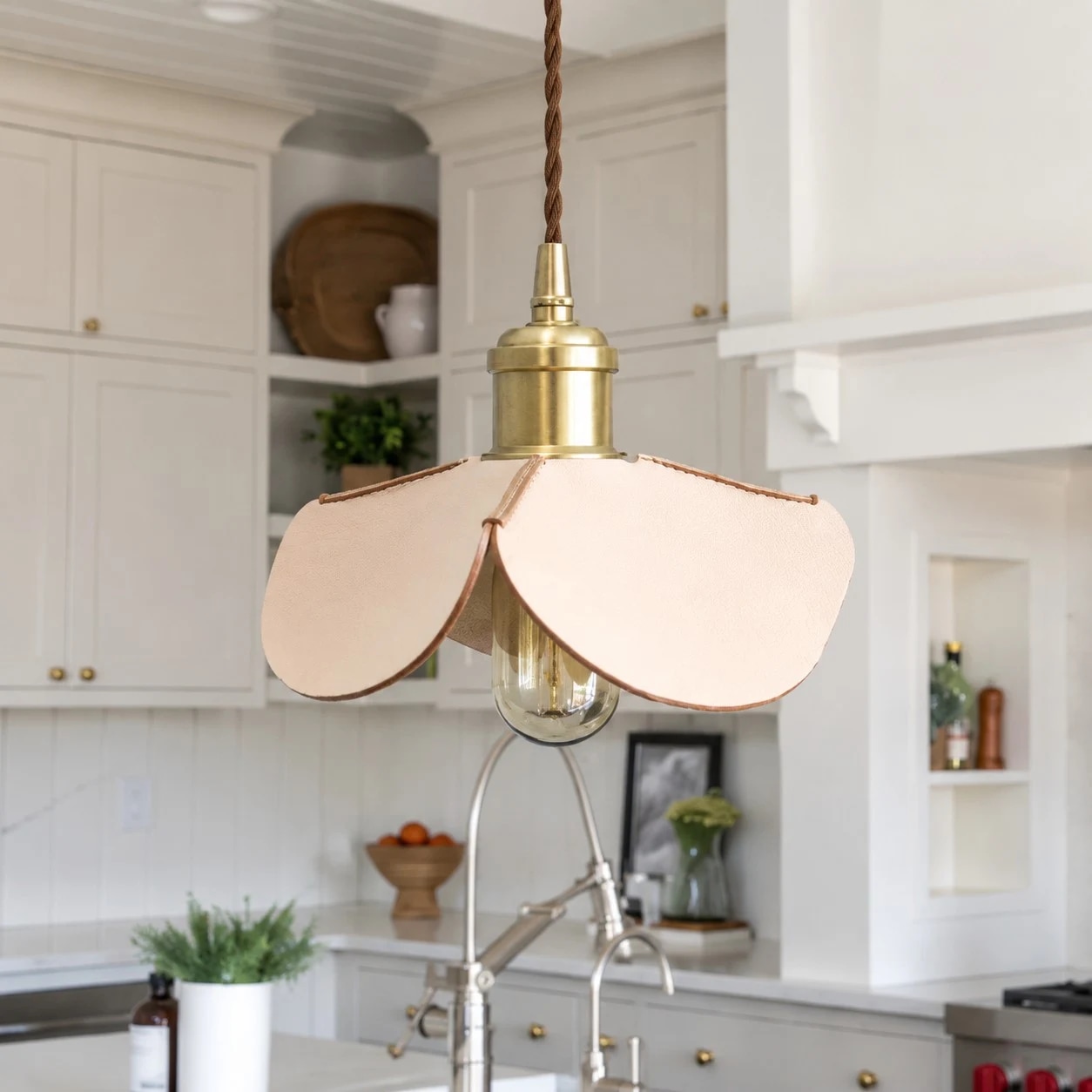 Suspension lumineuse en cuir cousue à la main, en forme de pétale, installée dans une cuisine lumineuse.