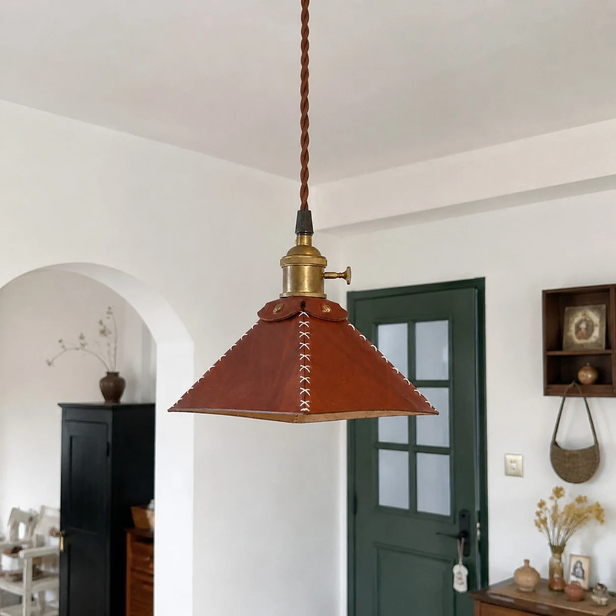 Leren piramidevormige hanglamp in een kamer met gewelfd plafond.
