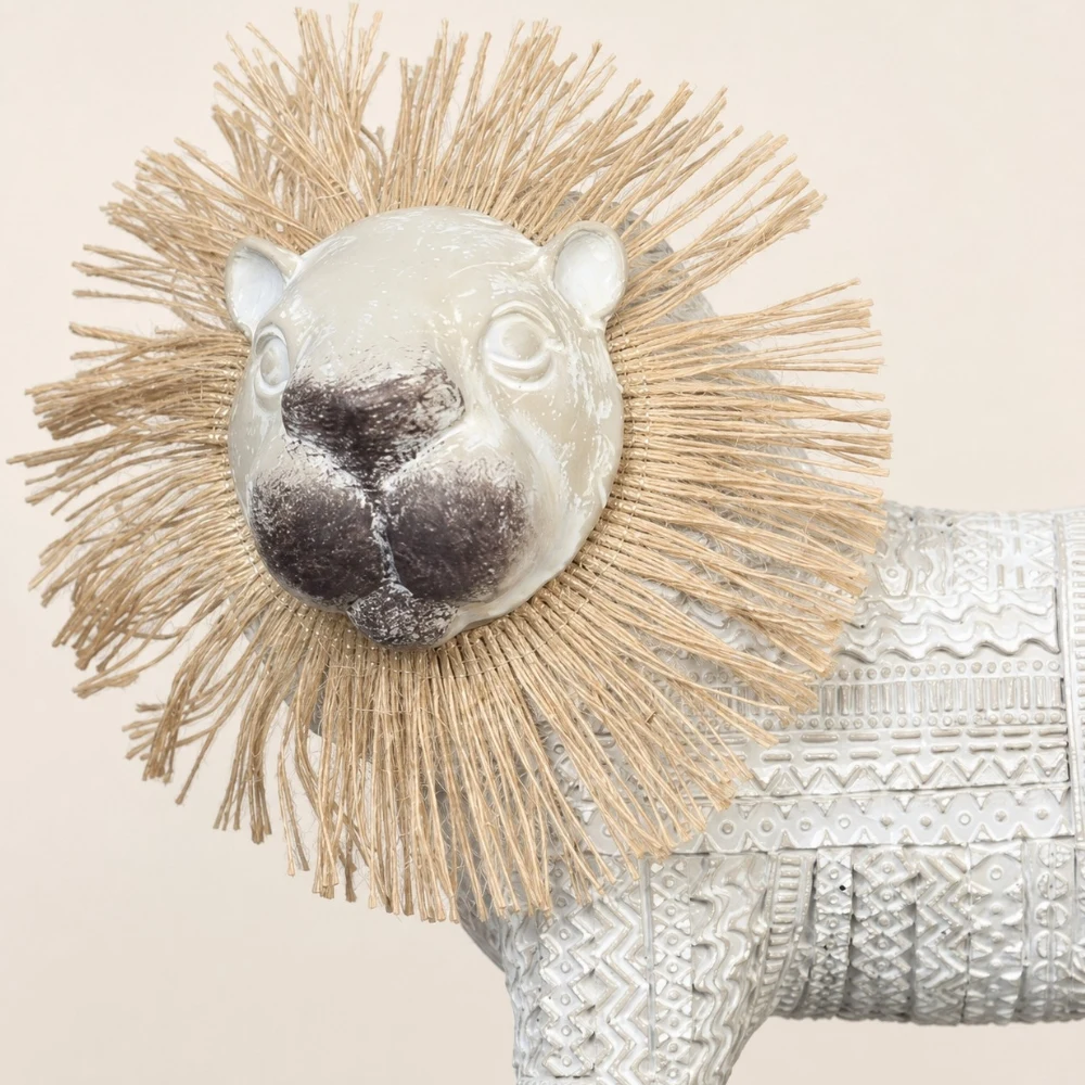 Detalle cercano de la melena tejida del león y su rostro brillante.