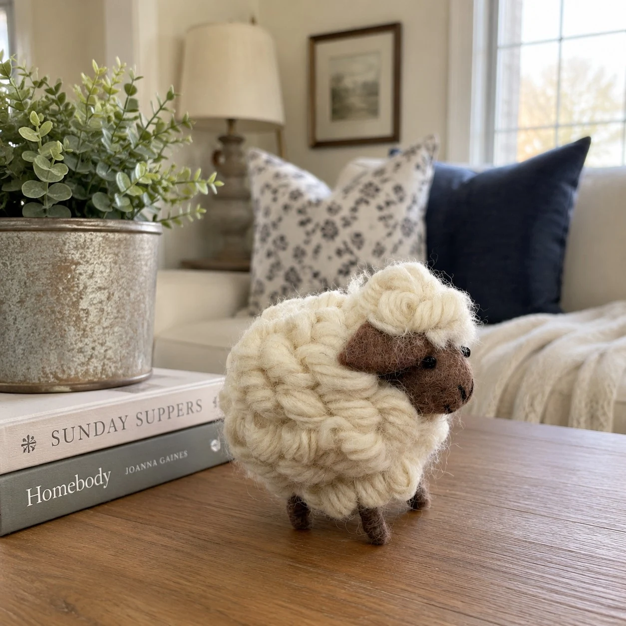 Figura de oveja hecha a mano, decorada con libros y vegetación.