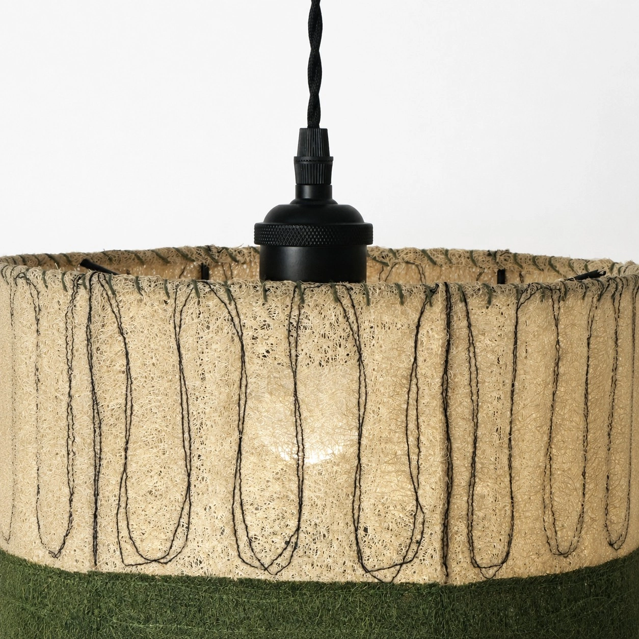Detailweergave van een matzwarte fitting en een loofah-lampenkap.