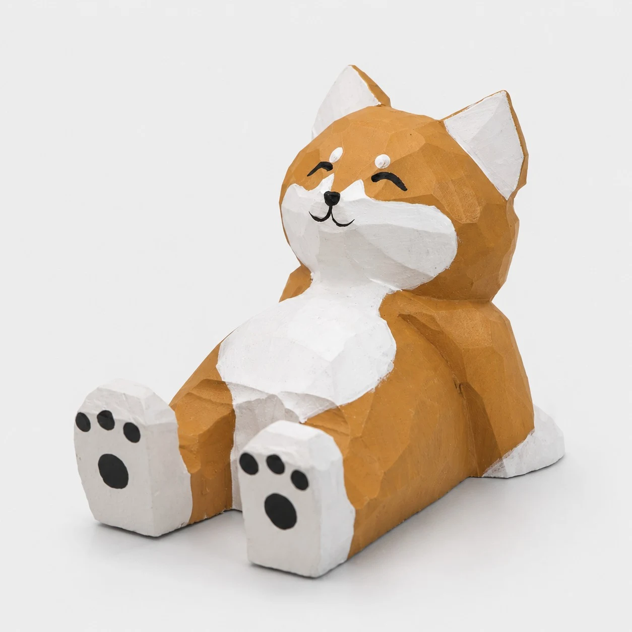 Supporto per telefono in legno intagliato a mano raffigurante uno Shiba Inu sdraiato.
