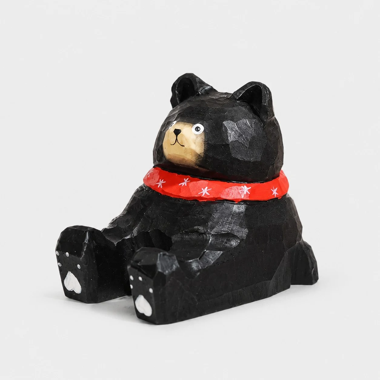 Supporto per telefono in legno intagliato a mano con orso nero e sciarpa rossa.