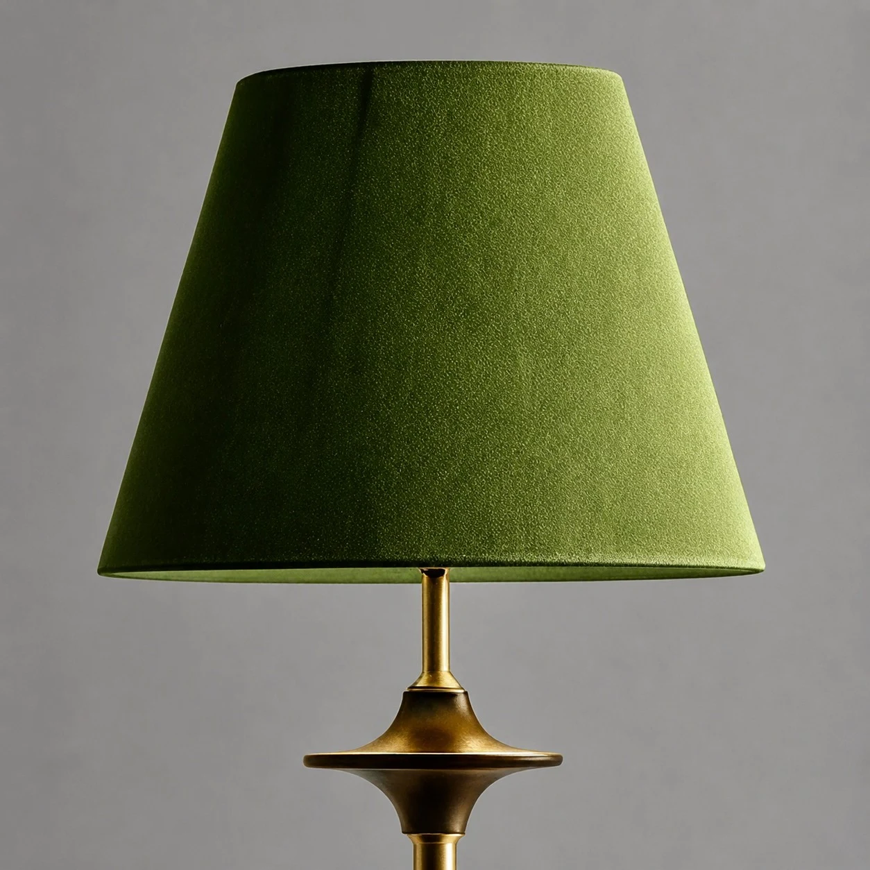 Pantalla de tela verde y tallo de lámpara en tono latón.
