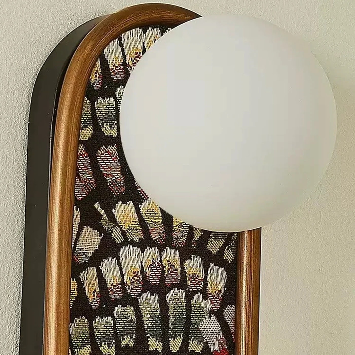 Dettaglio dell'applique da parete con paralume a globo e tessuto decorato.