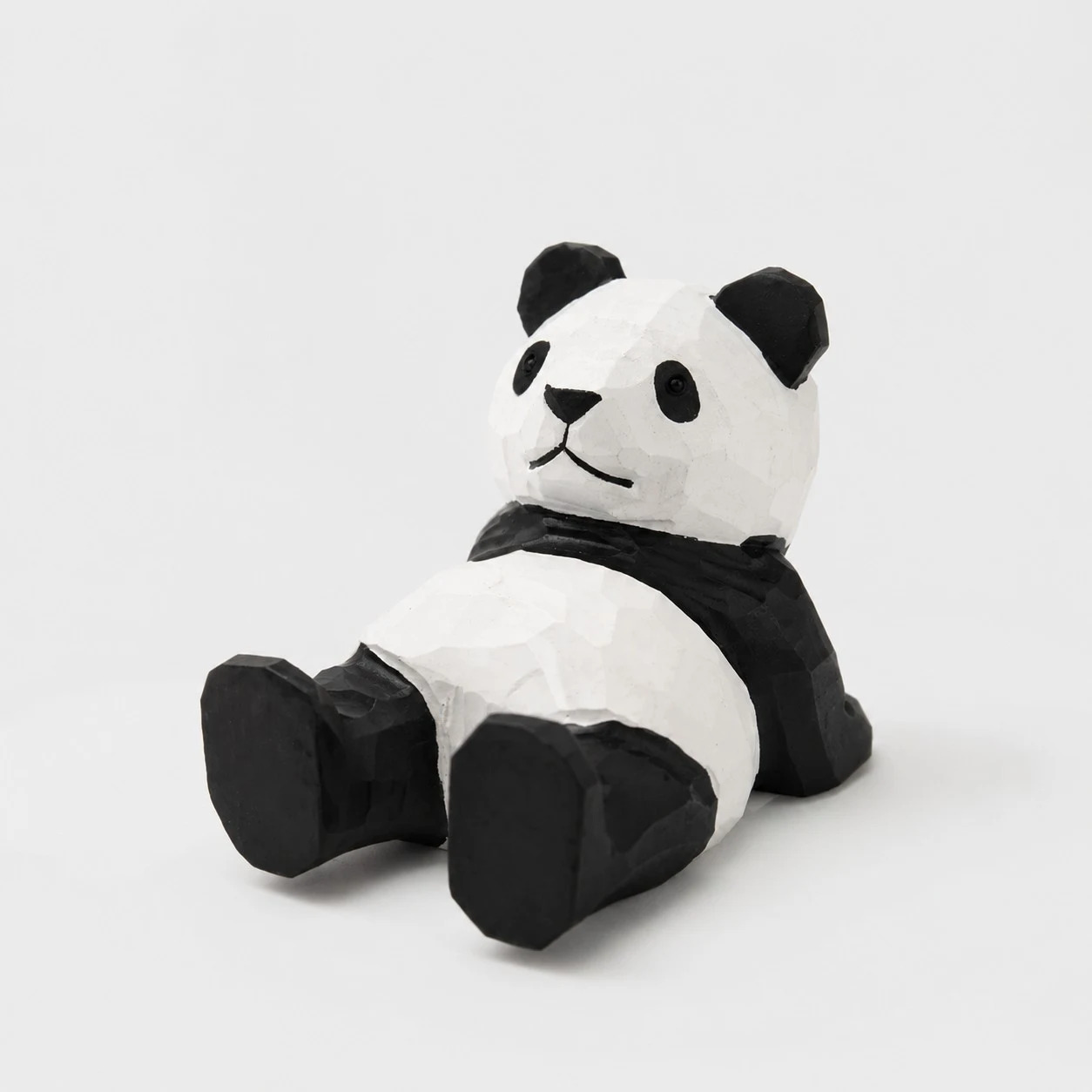 Supporto per telefono in legno intagliato a mano a forma di panda sdraiato.