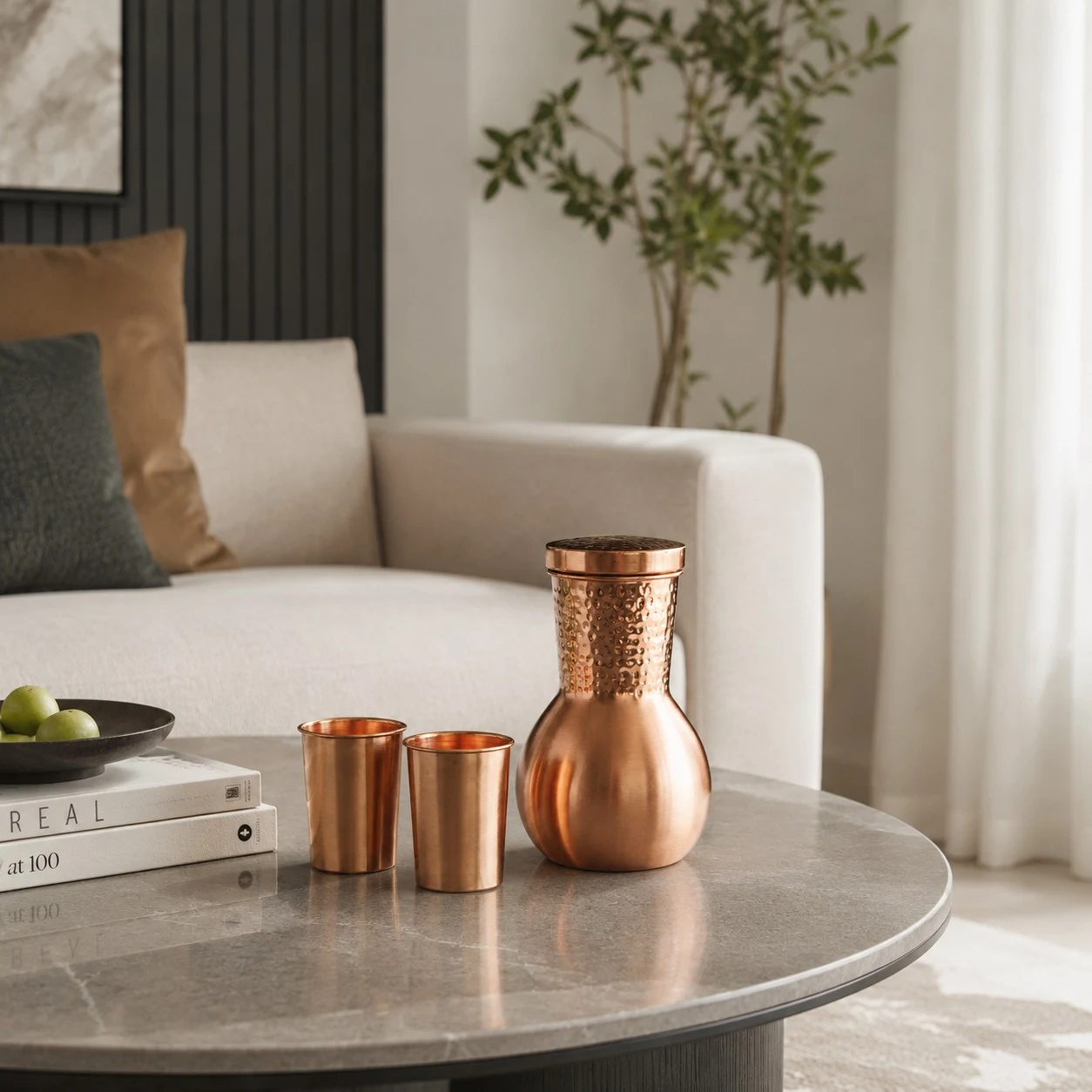 Tetera y tazas de cobre dispuestas con estilo sobre una mesa de salón.