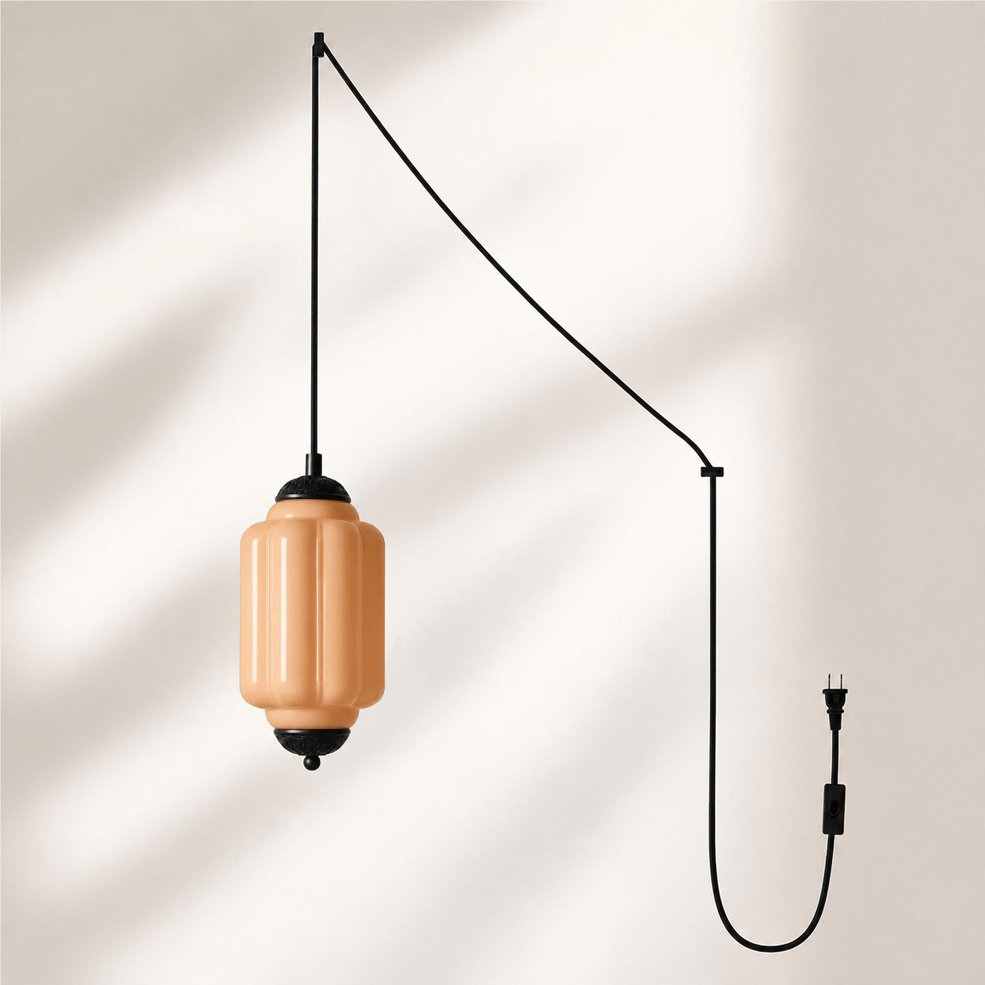 Lampadario a sospensione con finitura nera e paralume in vetro arancione.