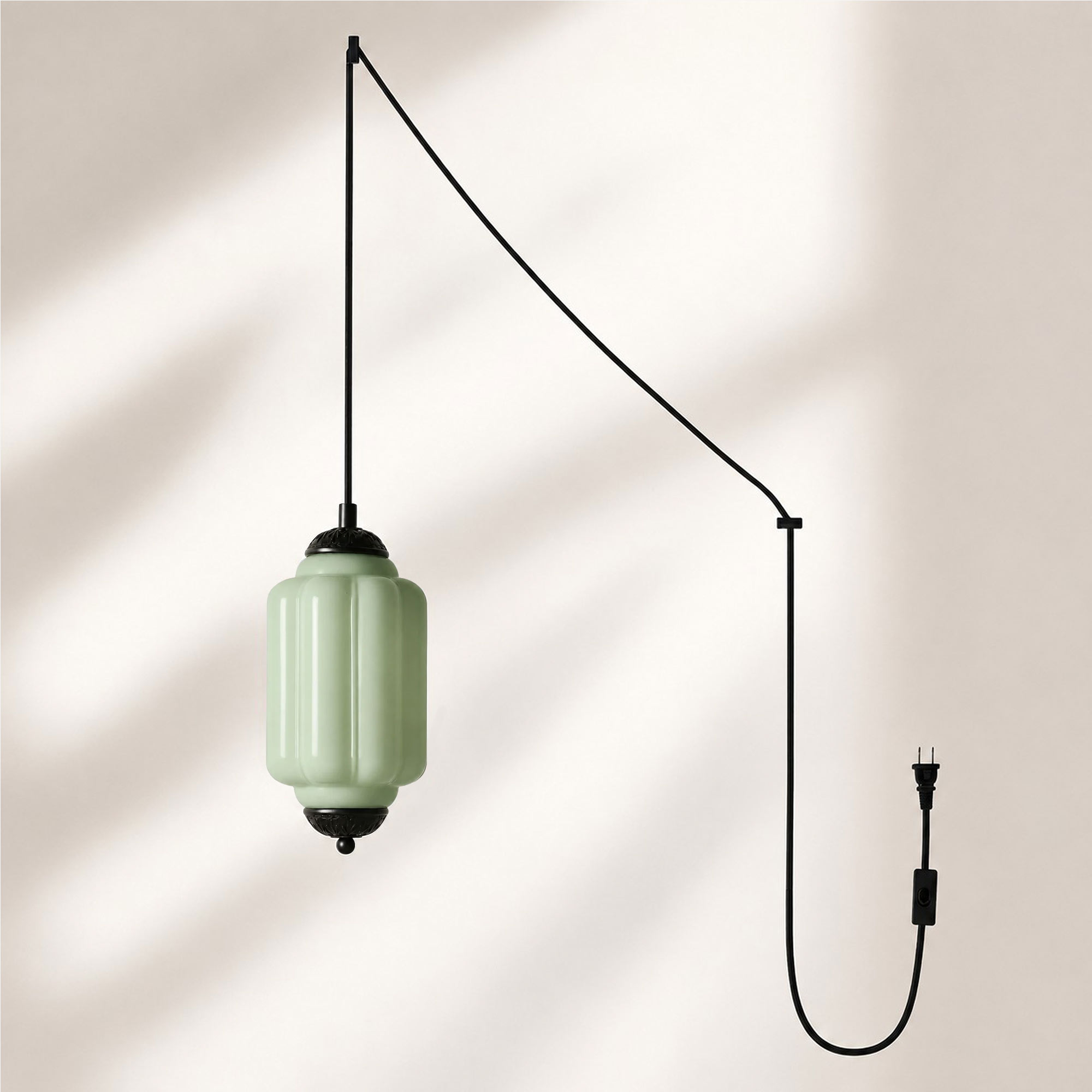 Lampadario a sospensione con finitura nera e paralume in vetro verde.