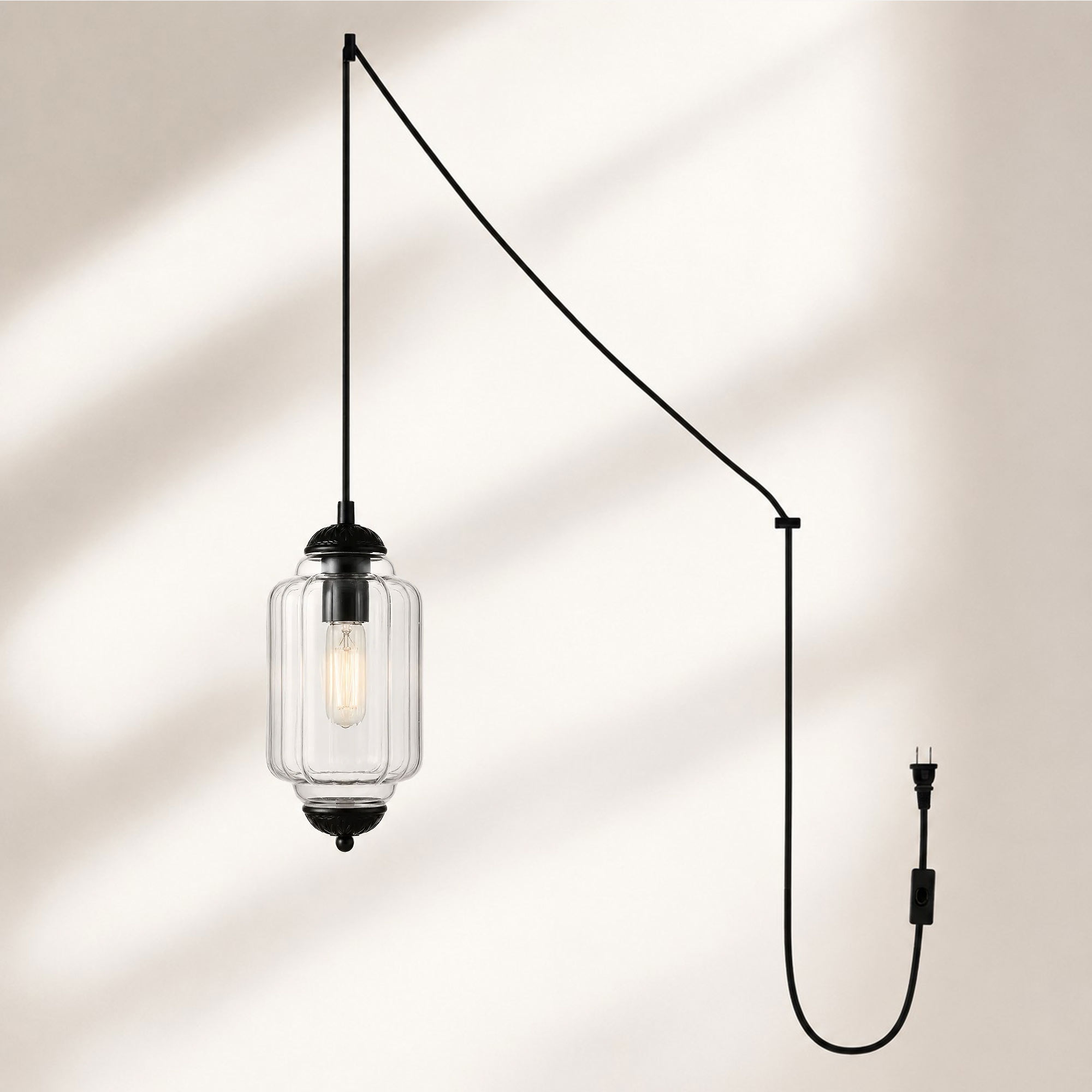 Lampadario con finitura nera e paralume in vetro trasparente.