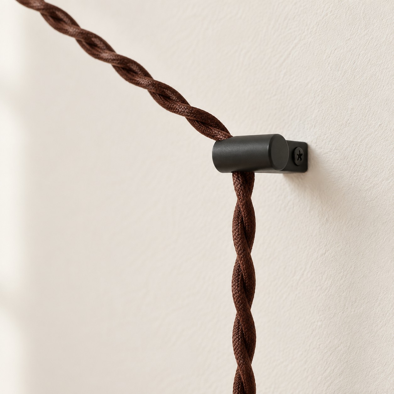 Primer plano del cordón trenzado marrón sostenido por un gancho de pared negro