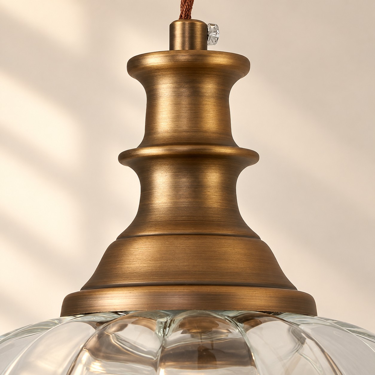 Close-up of stepped brushed brass collar on fluted glass
