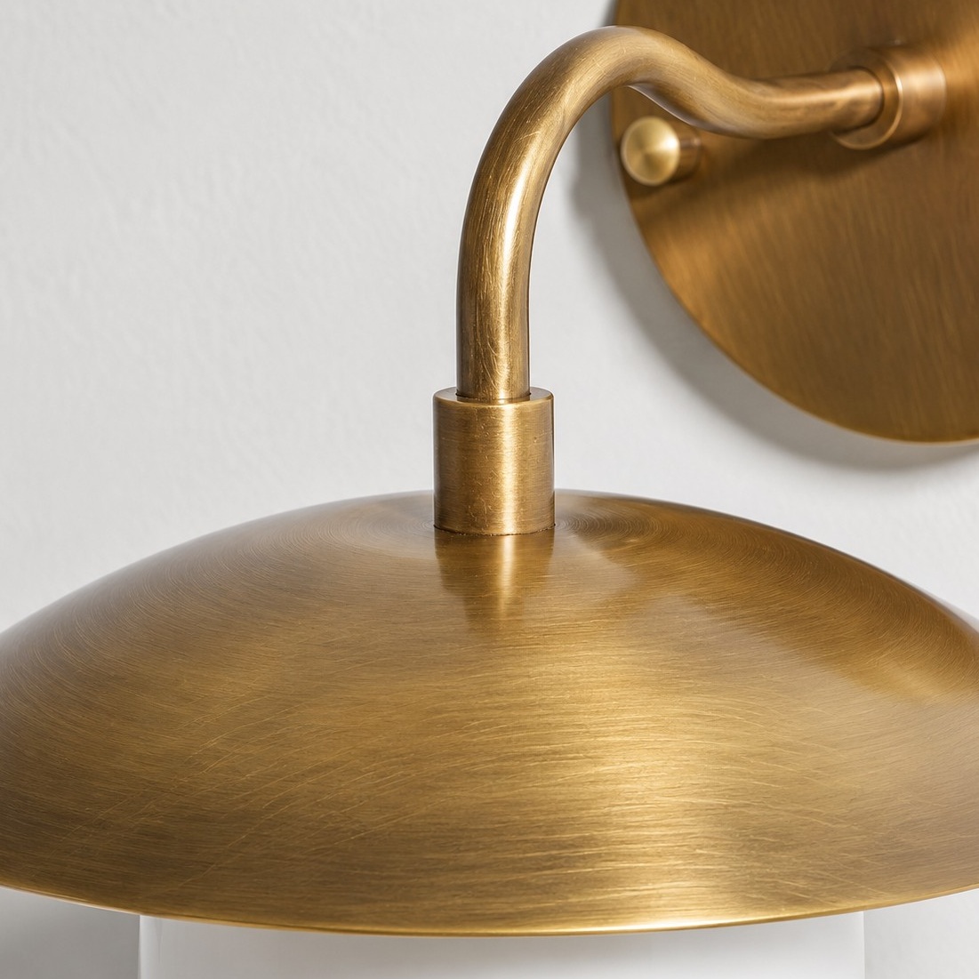 Burnished brass arm and wall plate of the sconce