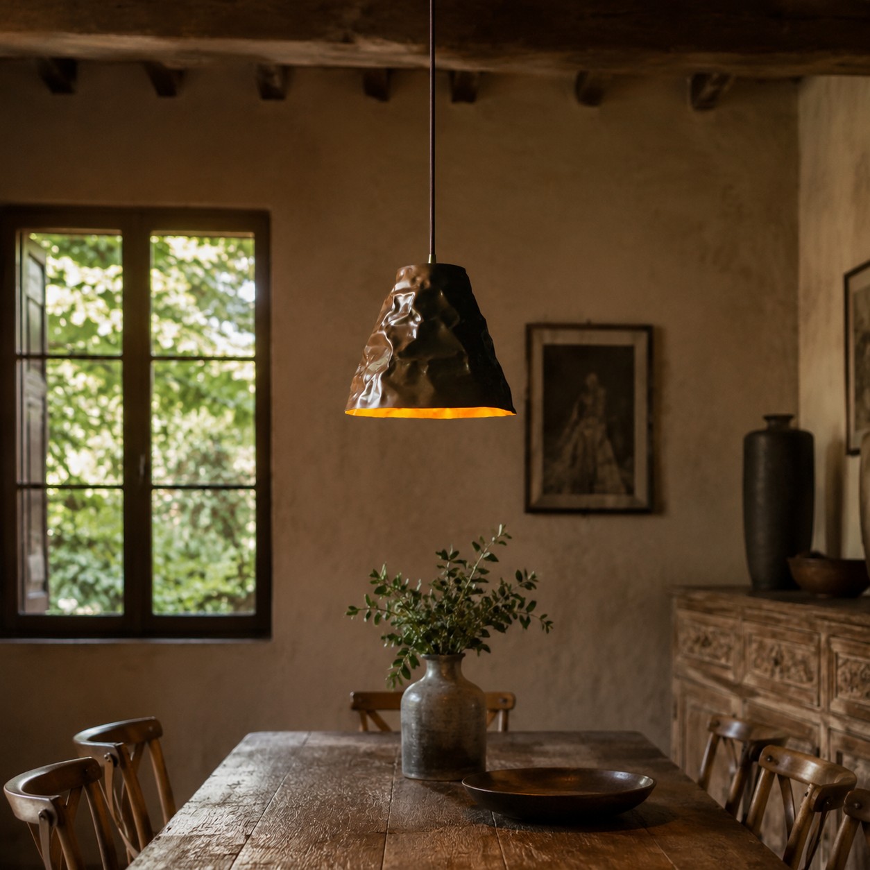 Primo piano della texture martellata sul paralume in ottone di una lampada a sospensione.