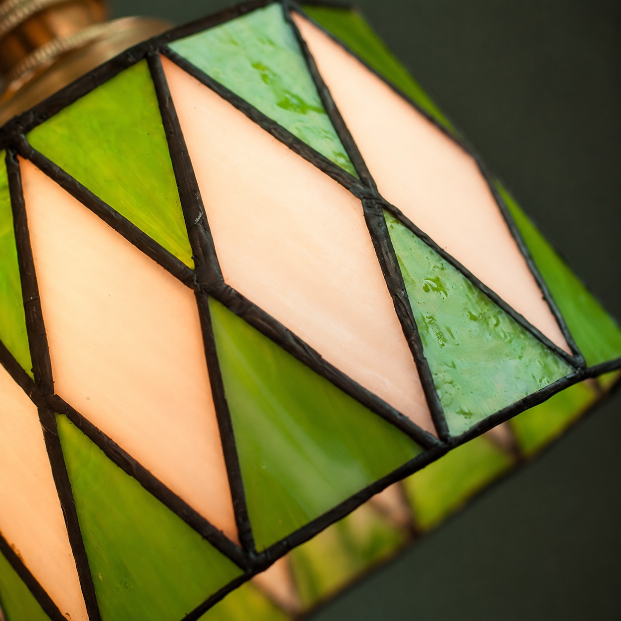 Luminária pendente de vitral verde em um ambiente.