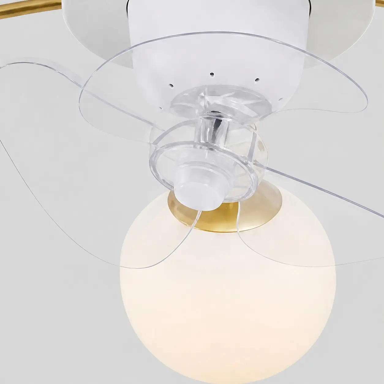 Gros plan sur les pales transparentes du ventilateur et les globes en verre blanc.