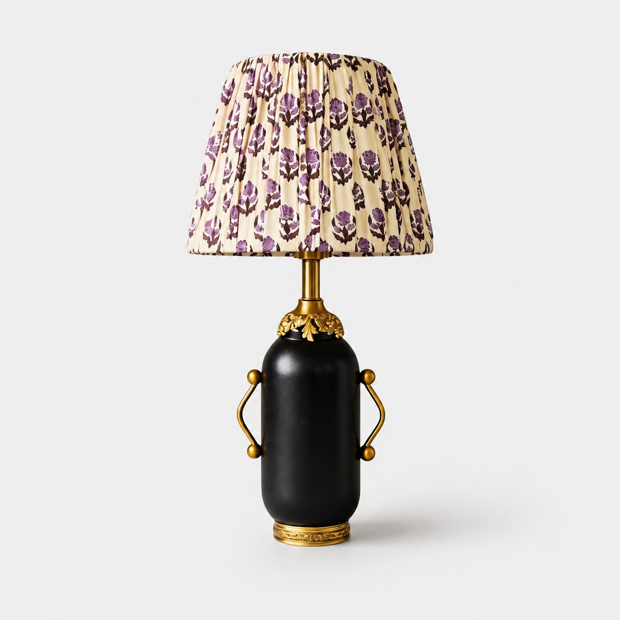 Lampada da tavolo nera opaca con paralume plissettato a fantasia floreale viola.