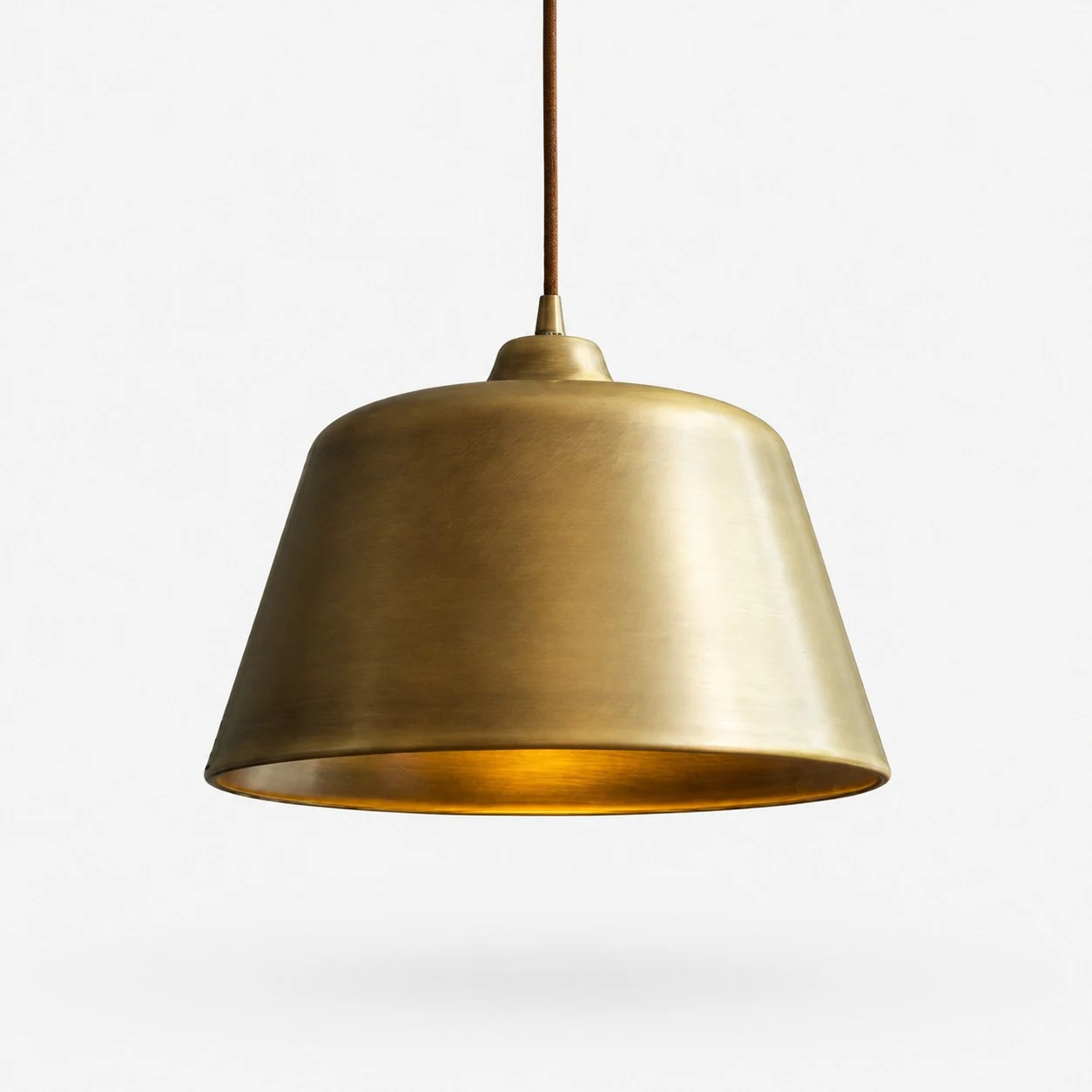 Luminária pendente em forma de sino, em latão antigo, sobre um fundo neutro.