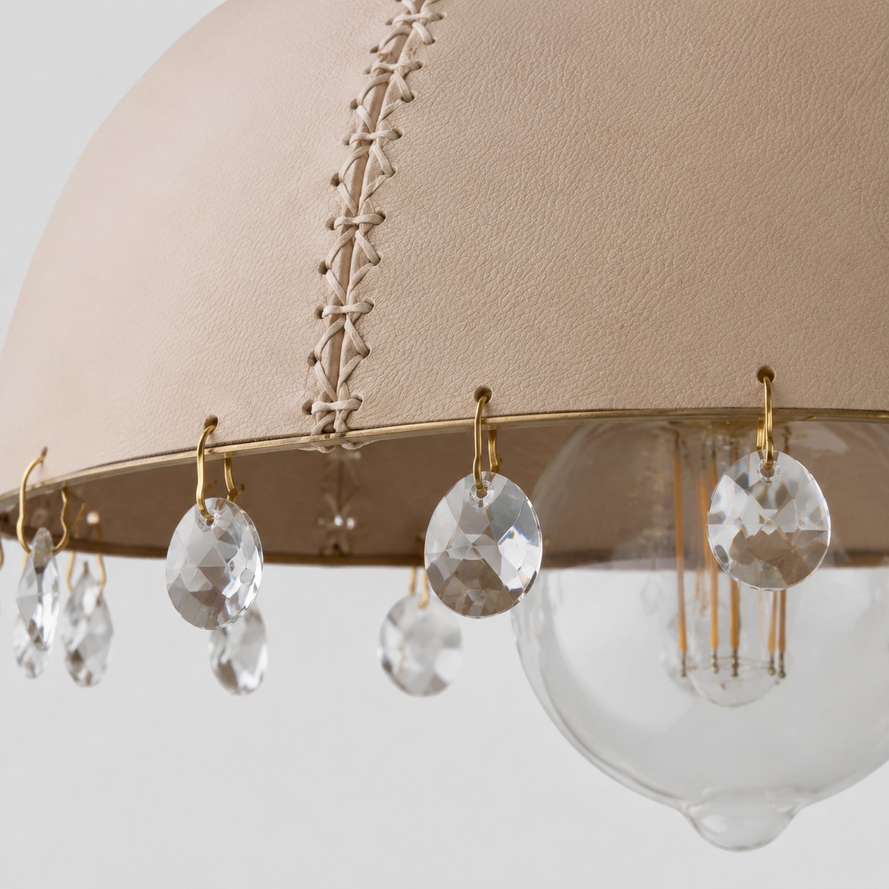 Dettagli in pelle, metallo e cristallo in un ciondolo compatto dalla silhouette elegante.