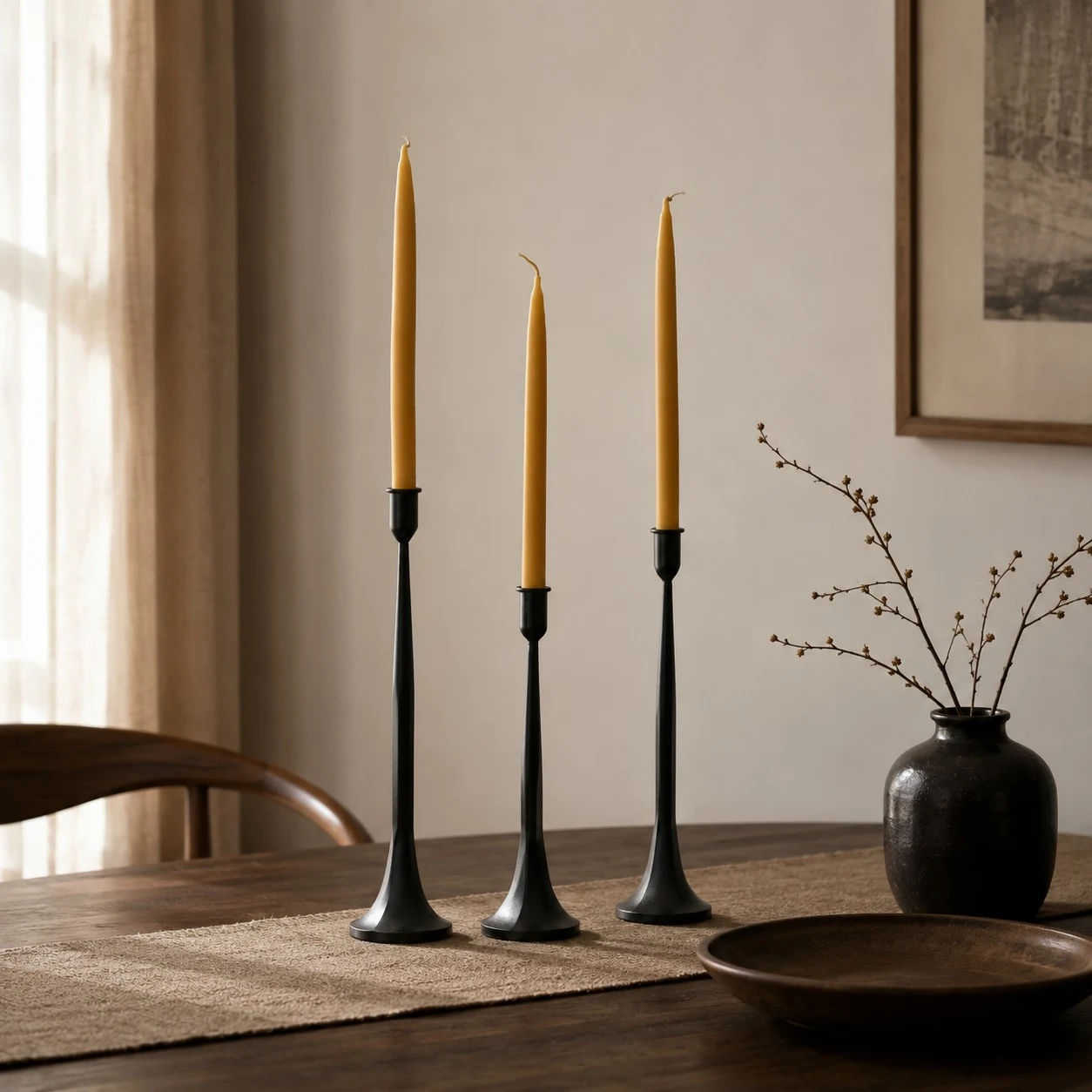 Three black iron candle holders styled in a calm dining room