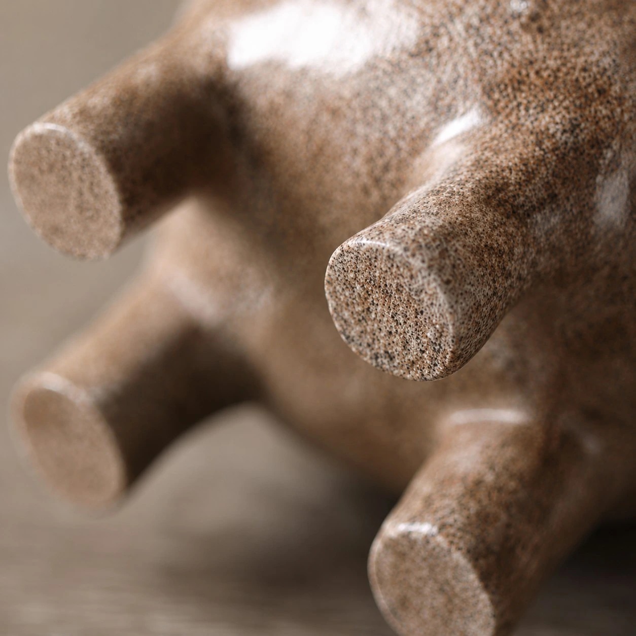 Close view of the sculpture's rounded feet and speckled finish