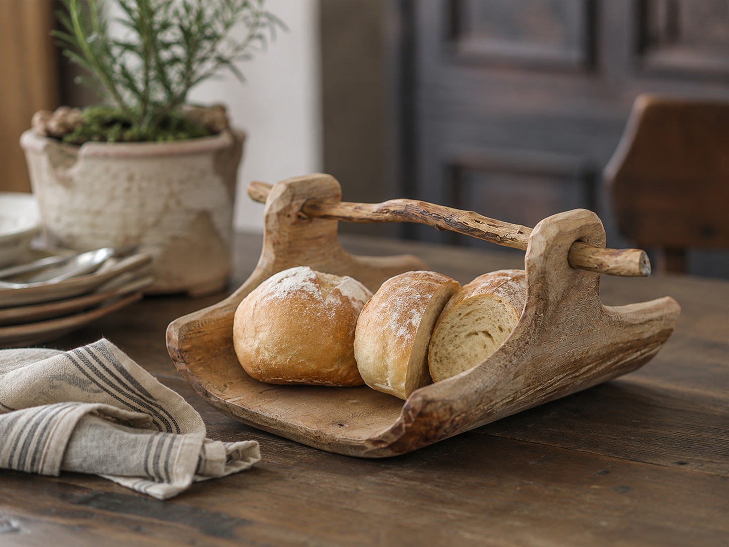 Willow wood tray holding bread on a rustic dining table