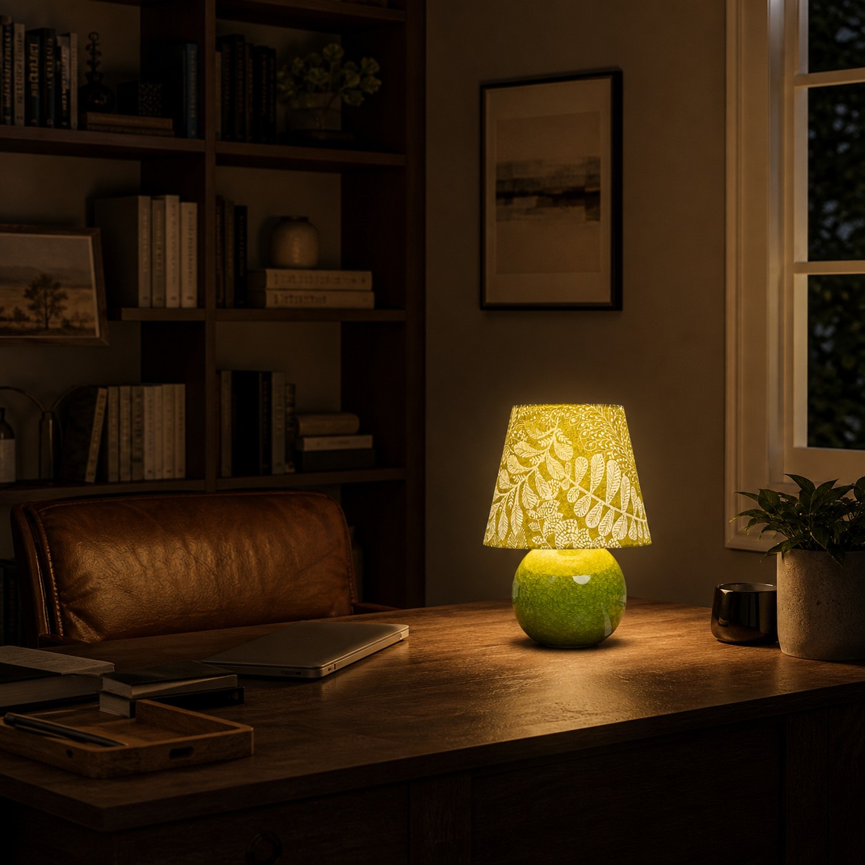 Eine botanische Tischlampe mit Olivenzweigen auf einem Schreibtisch in der Abenddämmerung