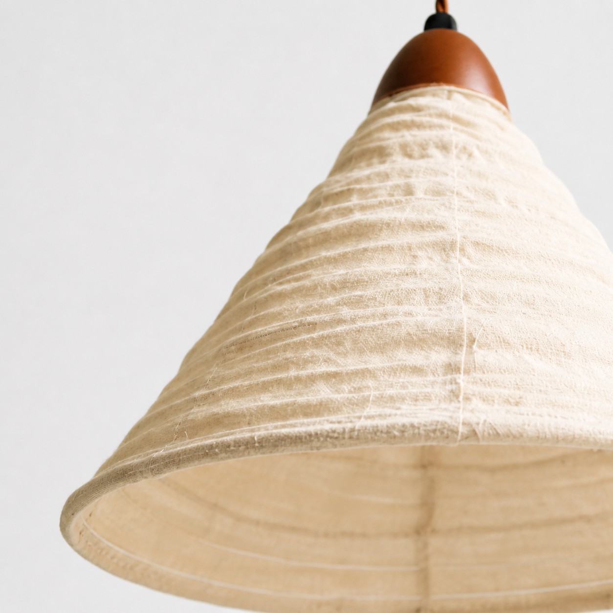Ivory fabric shade with visible pleats, stitching, and shaped edge
