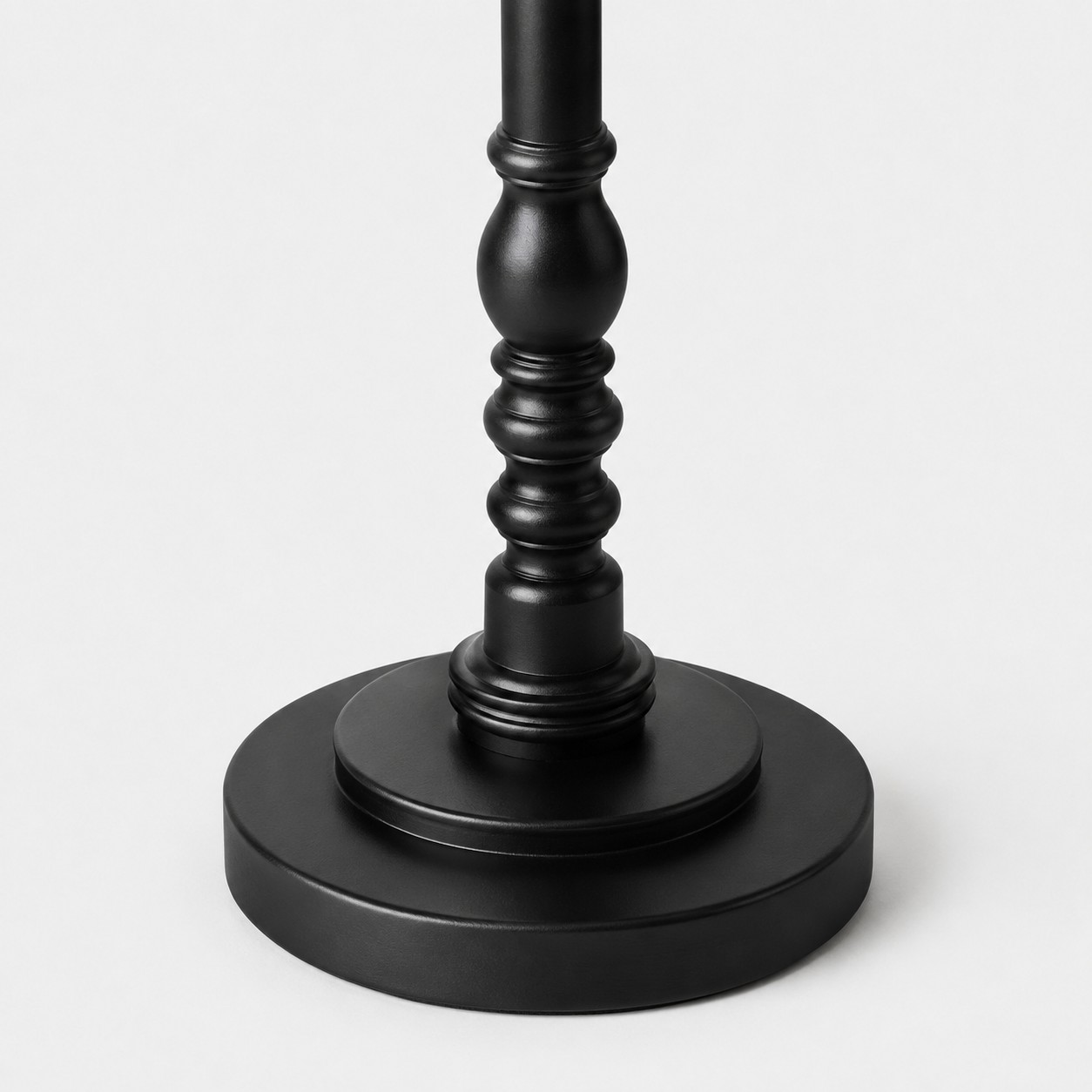 Close view of the black circular base and lower turned-wood detail