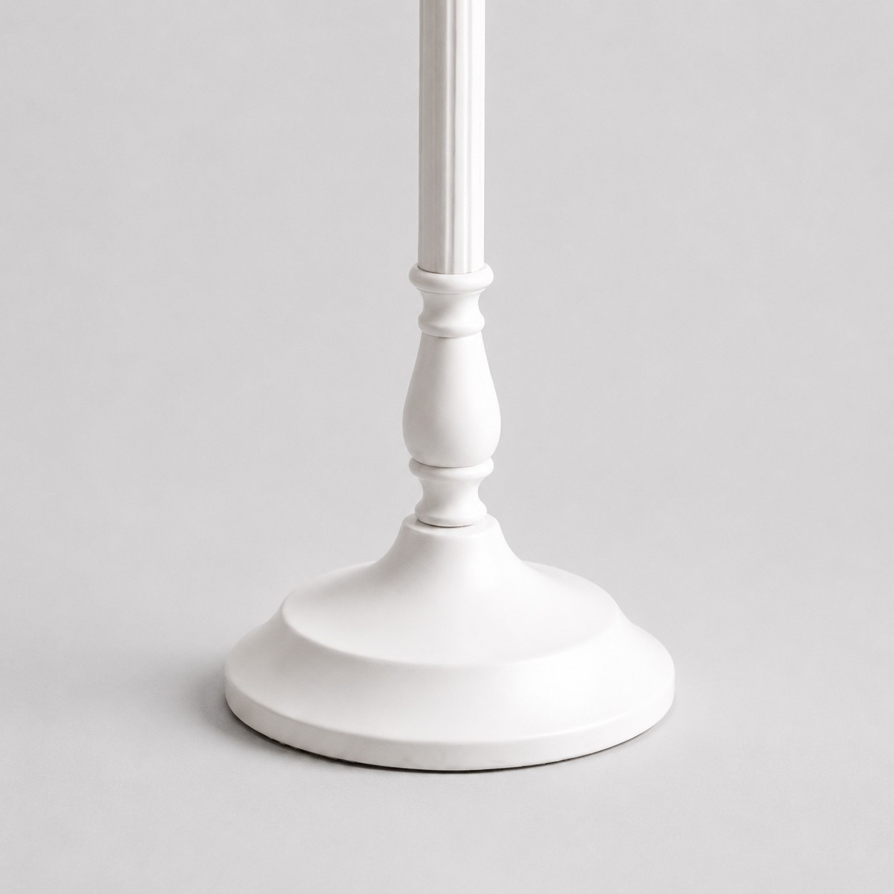 Gros plan sur le socle rond festonné de la lampe de table en métal blanc