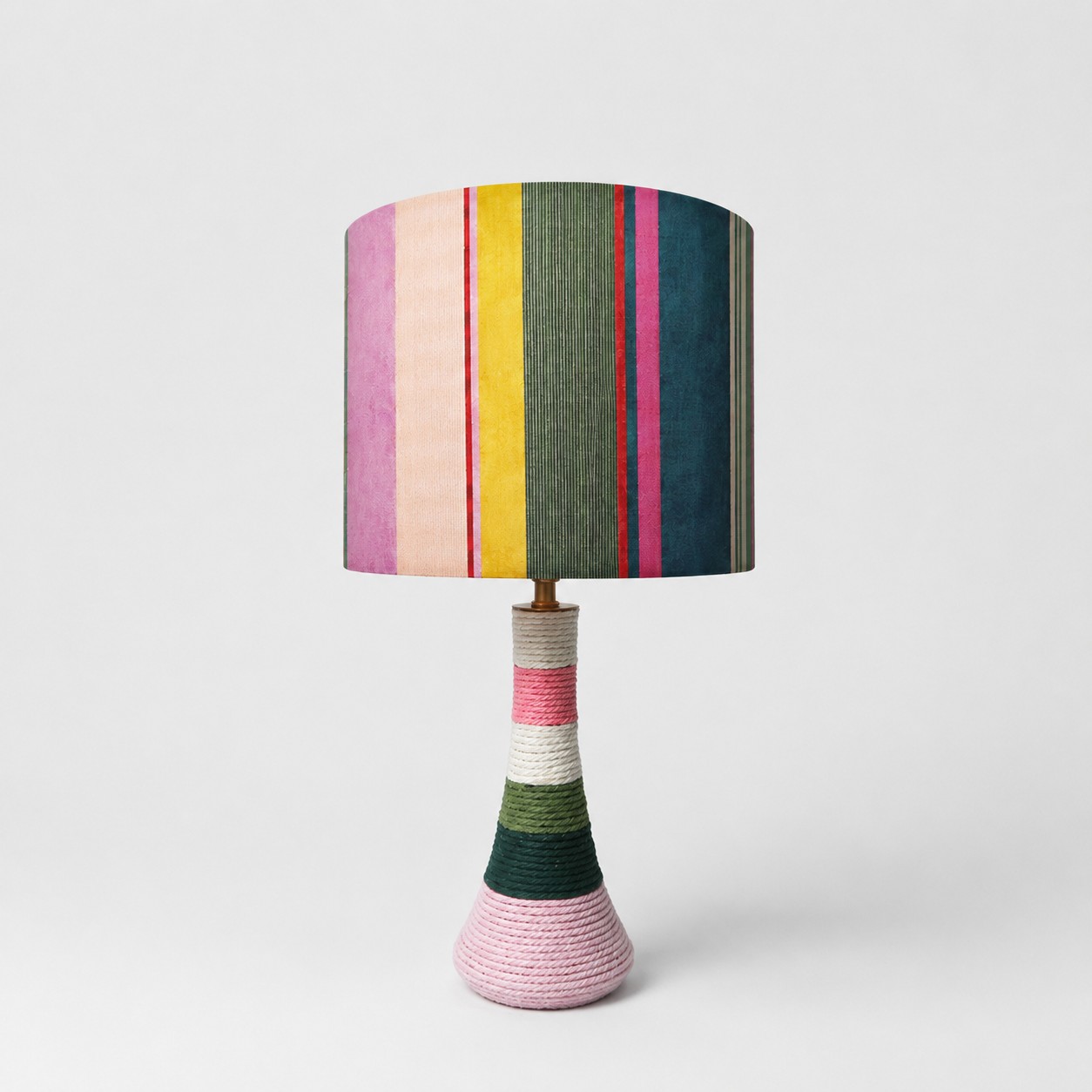 Colorful striped fabric table lamp with thread-wrapped base on white background