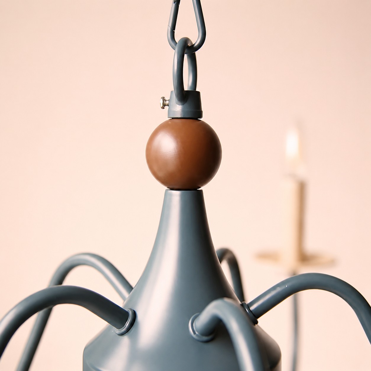 Lustre francês para velas com detalhe superior em tom de madeira e braços curvos.