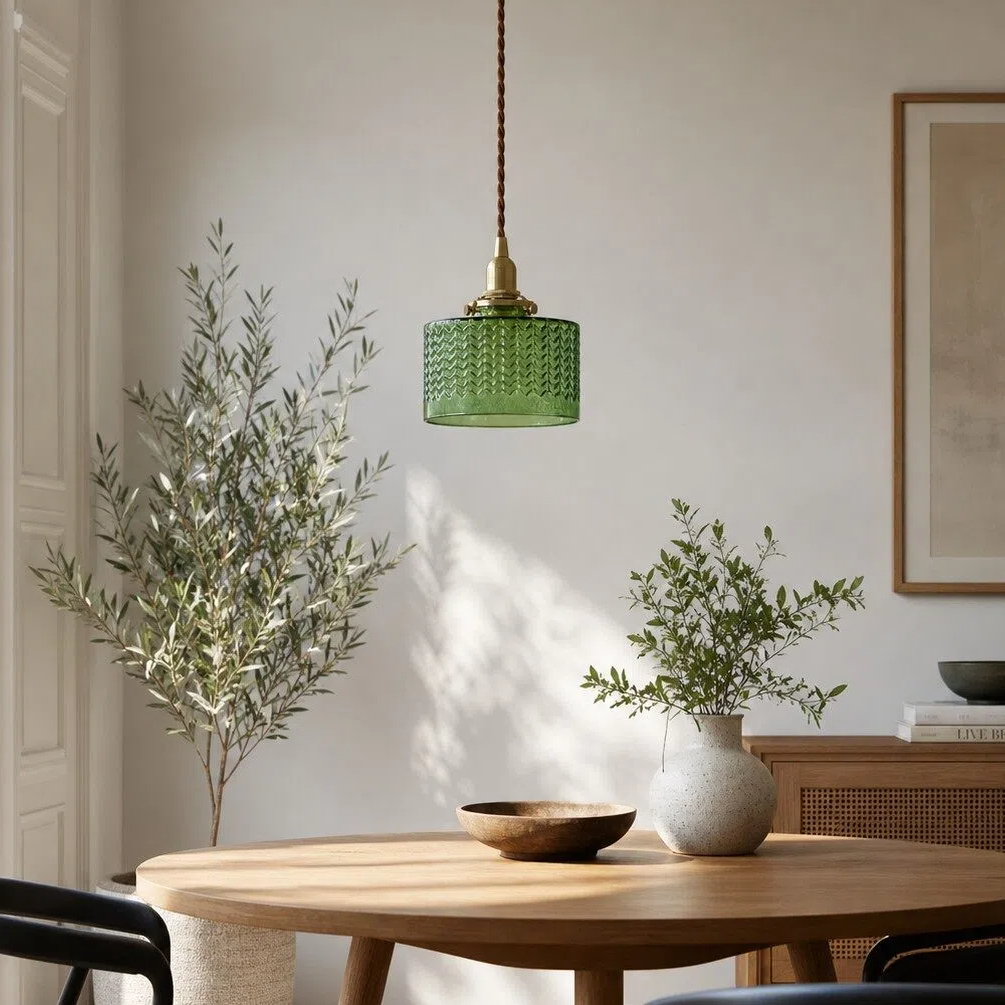 Lampadario a sospensione in vetro color smeraldo sopra un tavolo da pranzo.
